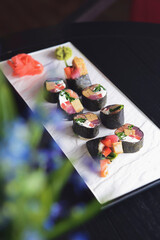 Maki Sushi set on a white plate over black background. Japanese cuisine concept, maki rolls.