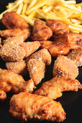 Hot spicy deep fried set. Deep fried checken, cheese camambert and french fries over black background.