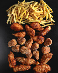 Hot spicy deep fried set. Deep fried checken, cheese camambert and french fries over black background.