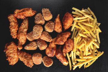 Hot spicy deep fried set. Deep fried checken, cheese camambert and french fries over black background.