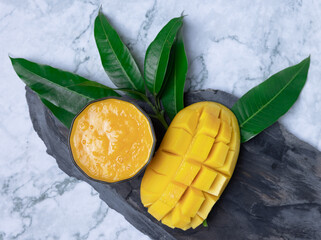 Mango smoothie in a glass and mango on wooden background.Mango shake.Tropical fruit concept.