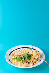 Traditional Italian pasta with clams and ruccola served in a white plate over blue background.