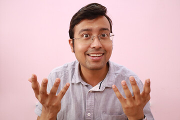Smiling Indian man showing an expressive speaking gesture isolated on a pink background
