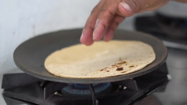Closeup shot of hands of an Indian female making roti in the kitchen