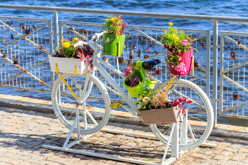 Fototapeta na wymiar Decorative bicycle shape stand for plants and flowers on the embankment by a sea