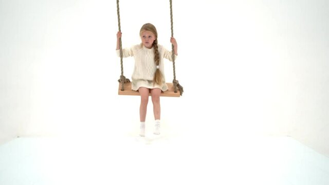 Cute long haired girl sitting on rope swing