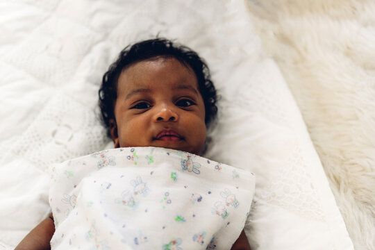 Portrait of cute adorable little african american baby looking in a white bedroom