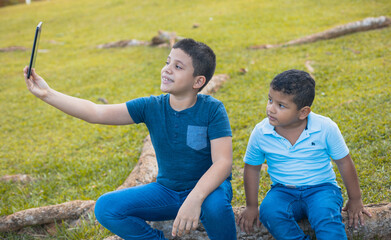 Pair of young hispanic brothers taking a selfie on a field