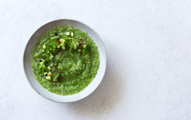 Cucumber gazpacho. Green cold cucumber cilantro celery  soup in gray bowl on gray stone background. Flat lay. Copy space