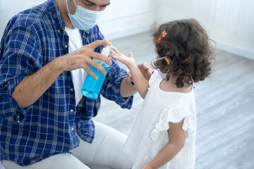Father giving and pouring alcohol hand wash gel to his daughter put on hand to protect her from coronavirus disease outbreak, covid-19 and pandemic concept, wear protection mask