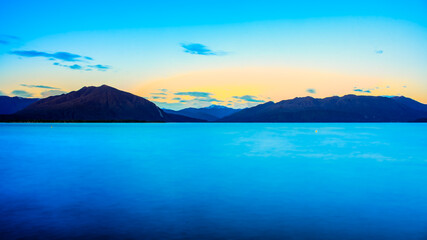 Long exposure at Lake Brunner very early morning as the sun rises above the Southern Alps mountain range  at sunrise