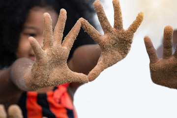 Close up hands, happy dark skinned girl show sand on hands  after playing with sand on white...