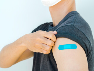 Vaccinations, bandage plaster on vaccinated people's arm concept. Blue color adhesive bandage on...