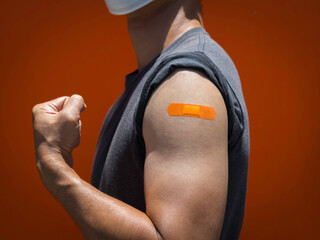 Vaccinations, bandage plaster on vaccinated people's arm concept. Orange color adhesive bandage on...