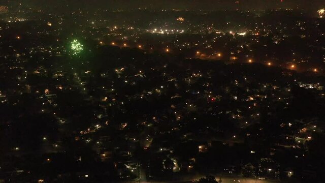 An aerial view of Fourth of July fireworks set off by the locals on Long Island, NY. The drone camera dolly in while tilted down over the suburban neighborhood as fireworks go off below.