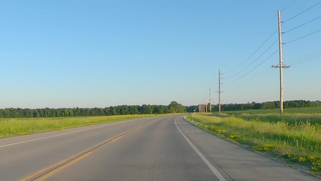 POV while driving on a rural county road thru the Midwest on a late spring afternoon; concepts of agriculture, freedom and open road