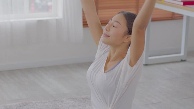 Calm of Athletic Asian woman in sportwear practice yoga Sun Salutation to breathing and meditation at home,Healthy woman doing yoga Surya Namaskar for warm up body,Wellness Yoga Healthcare Concept