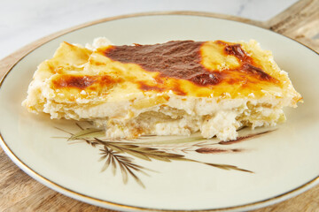 Casserole pie with cheese and sorrel on plate on light background