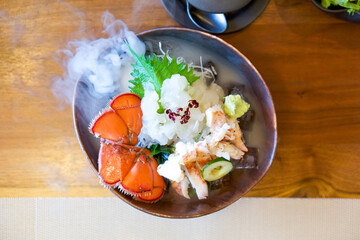 Live Canadian Lobster sashimi on brown ceramic plate with a smoke of dry ice. Served two ways fresh...