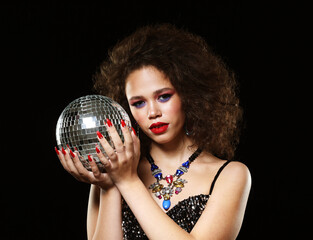 Naklejka premium Portrait of young beautiful african woman with creative make up holding disco balls over black background