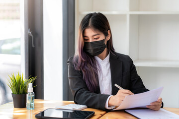 Asian businesswoman wearing a mask working at the office.