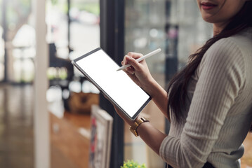 Close-up woman standing using stylus on digital tablet blank white screen at office.