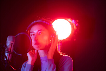 Beautiful Asian young woman perform a sing in the sound recording studio. 