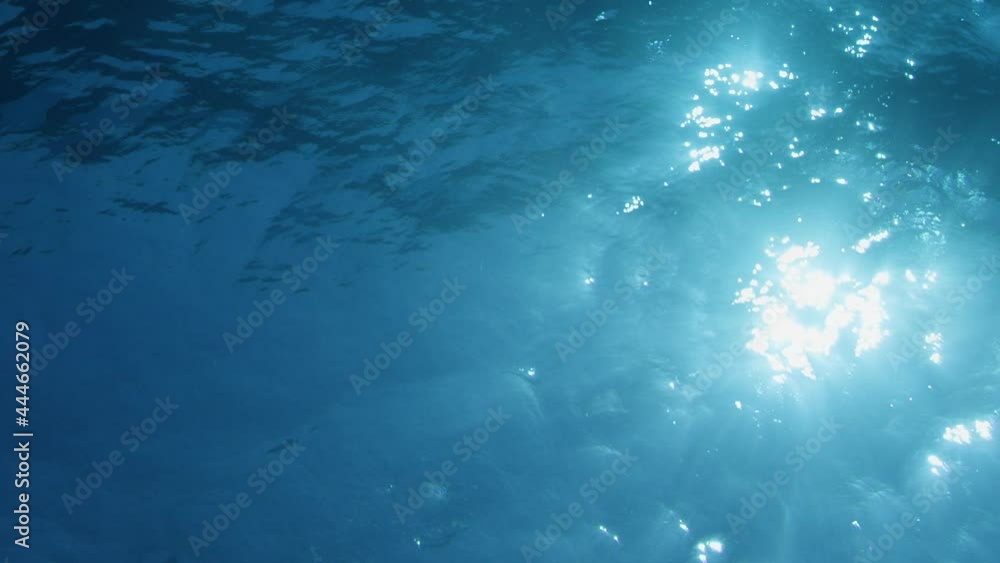 Poster light playing through the ocean surface seen from below. underwater background vfx element.