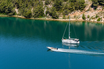 High angle image of sailboat and motorboat on sea near coast.