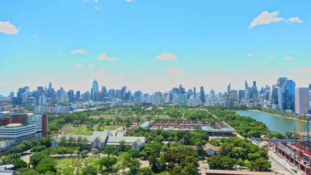 Queen Sirikit National Convention Centre construction site near Benjakitti Park and Lake, Millenium Residence Apartment, CTI Tower, Ocean Tower in Bangkok, Thailand on Sunny day time-lapse