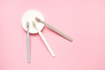 Gray and white toothbrushes on pink background.Taking care of teeth, dental concept. Flat lay photo, copy space, top view.
