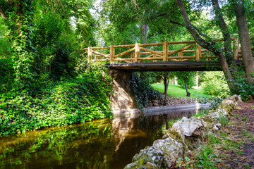 Fototapeta na wymiar Wooden bridge over a small stream in the Retiro public park, Madrid.