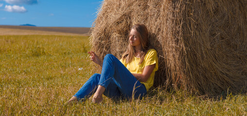 Naklejka na ściany i meble a girl is sunbathing in the hay. village life: harvesting hay for the winter. animal feed.