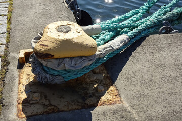 Fototapeta premium Close up of rusted yellow mooring bollard on the pier with blue naval rope on a sunny summer day. Marine. Noblessner, Tallinn, Estonia