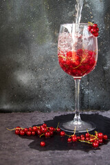 Red currant in the wineglass on the gray and blue background. Large group.