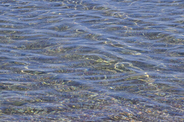 Transparent clear sea water and pebble bottom shining through it