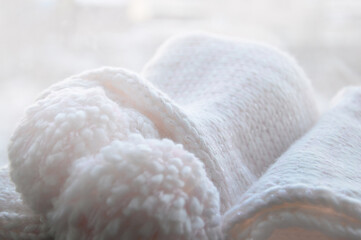 Rolled up knitted light pink scarf. Pastel background with knitted texture.