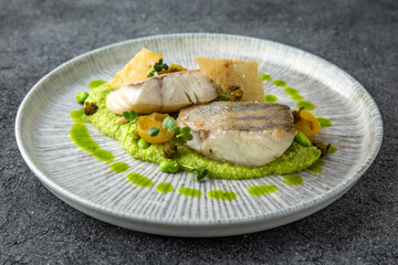 Fillet of white fish grilled or steamed with spinach puree. Diet nutritious meal. Ready menu for the restaurant. Neutral gray blue textured background