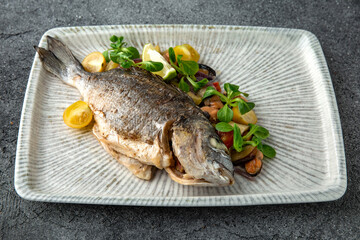 Dorada with steamed vegetables. Ready menu for the restaurant. Neutral gray blue textured background