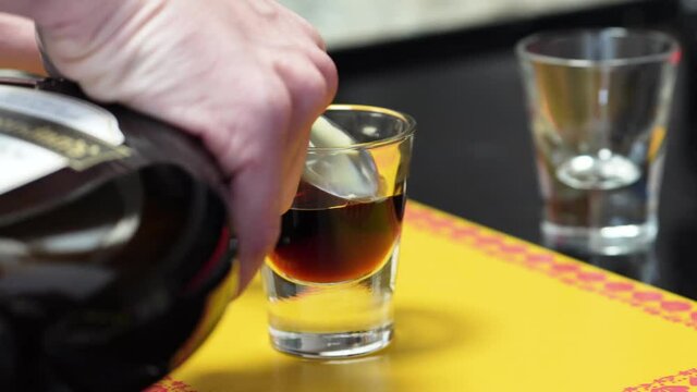 Hands Pouring Irish Cream Into Coffee Liqueur In A Glass Through The Back Of A Cold Spoon. B-52 Shot Layering Technique. close up