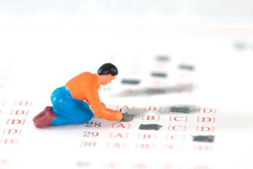 The miniature figure is lying on the answer sheet to erase the wrong option