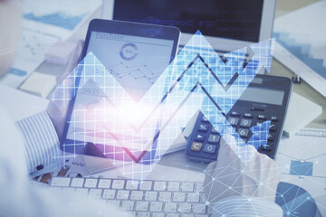 Double exposure of man's hands holding and using a digital device and arrows hologram drawing. Success concept.