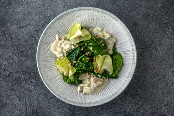 Hearty salad with mushrooms and chicken in a creamy sauce, zucchini and spinach with pine nuts. Diet food. Ready menu for the restaurant. Neutral gray blue textured background
