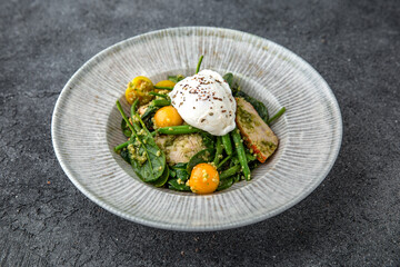 Diet nutritious meal. Green beans with pieces of chicken or turkey fillet with cherry tomatoes and poached egg. Ready menu for the restaurant. Neutral gray blue textured background