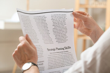 Naklejka premium Mature man reading newspaper at home, closeup