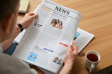 Mature man reading newspaper at home, closeup