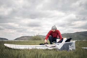 Windsurfer and camper packing and unpacking in nature.