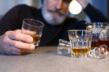 Senior man with glass of drink late in evening at home, closeup