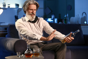 Senior man refusing to drink whiskey late in evening at home