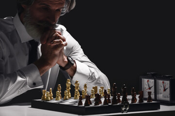Senior man playing chess on dark background